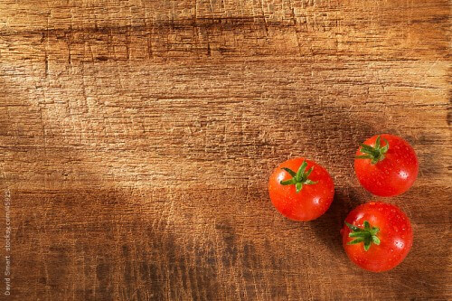 Whole tomatoes on rustic cutting board